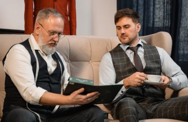 Tailor and client reviewing fabric samples for a custom suit in a stylish workshop.
