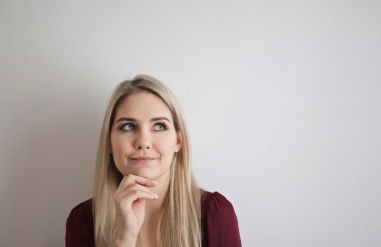 Portrait of a pensive woman with a thoughtful expression against a white background.